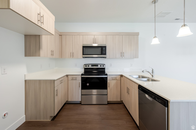 4727 South 690th West, Unit W201 Mapleton, UT 84664 - Photo 10 of 15 U-shaped kitchen featuring light wood-finish cabinetry, light-toned countertops, stainless steel appliances, and pendant lighting