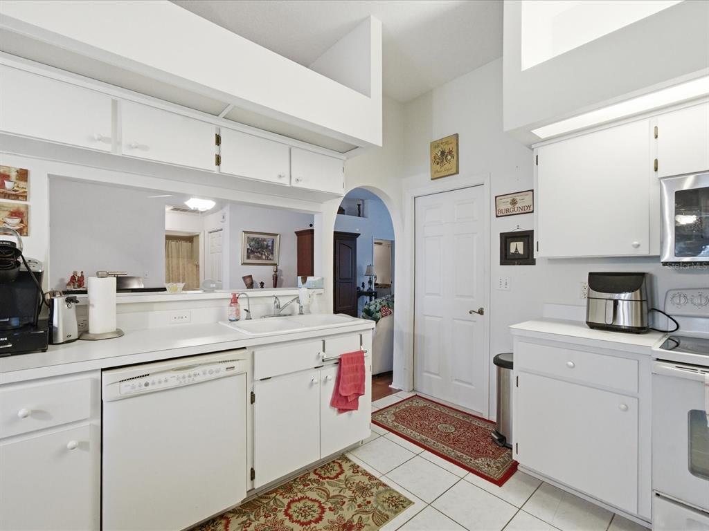 4209 Avanti Circle New Port Richey, FL 34655 - Photo 17 of 35 a kitchen with a sink dishwasher and white cabinets with wooden floor