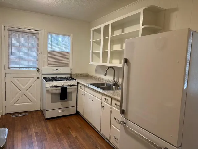a kitchen with granite countertop white cabinets and white appliances