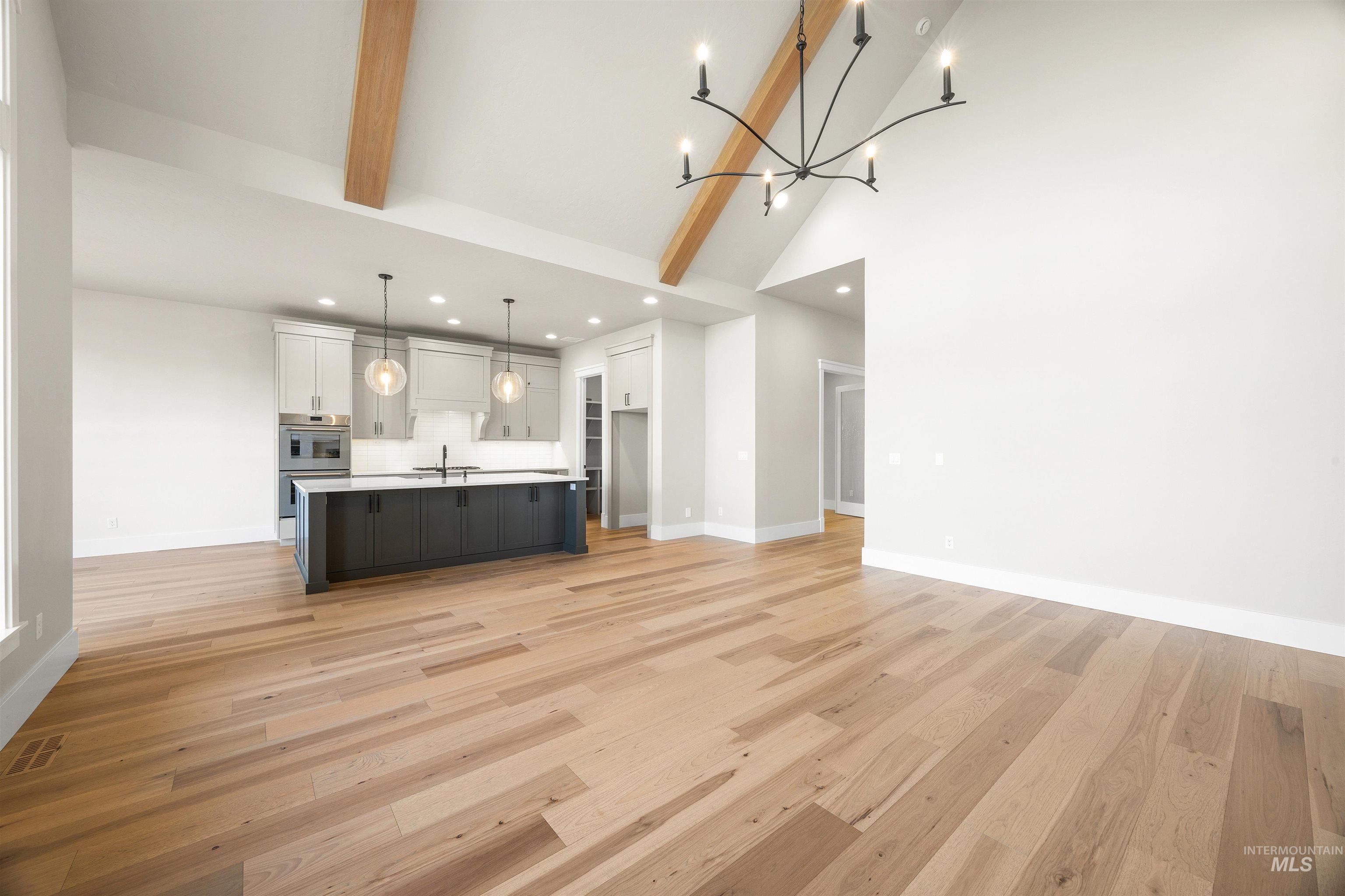 1126 East Crescendo Street Meridian, ID 83642 - Photo 13 of 48 Unfurnished living room featuring light wood-type flooring, hanging lights, and vaulted ceiling