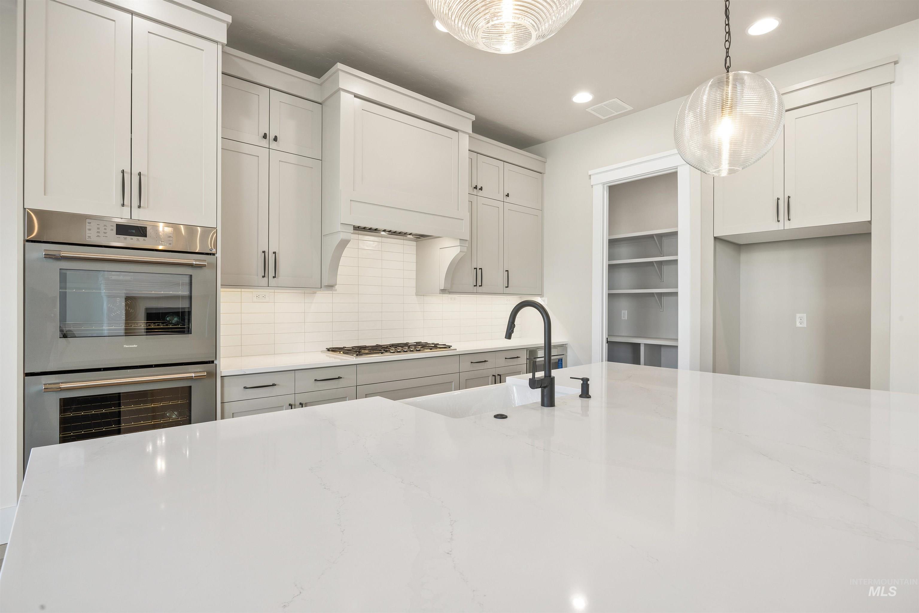 1126 East Crescendo Street Meridian, ID 83642 - Photo 19 of 48 Kitchen featuring backsplash, light stone countertops, stainless steel appliances, pendant lighting, and white cabinets