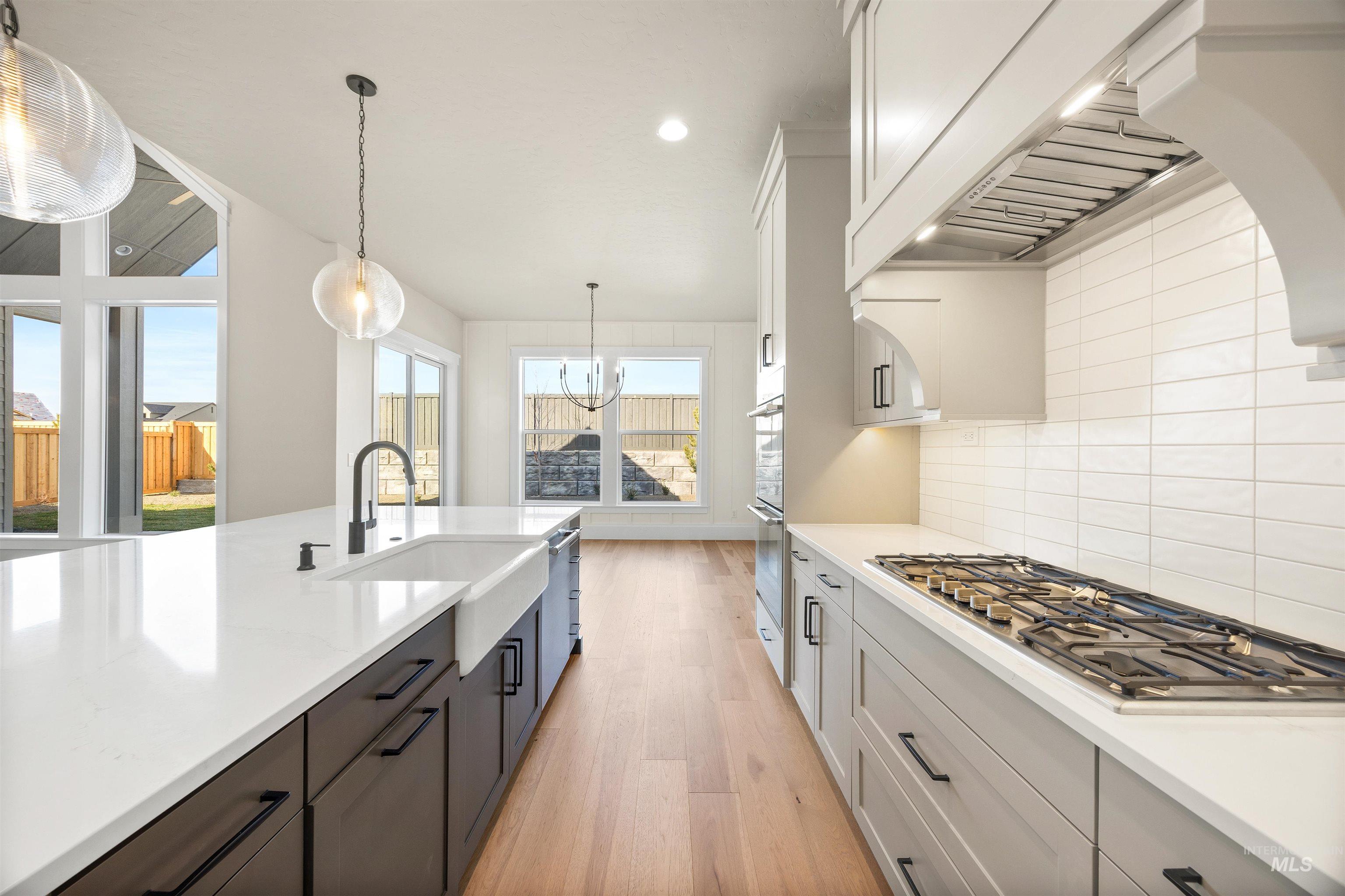 1126 East Crescendo Street Meridian, ID 83642 - Photo 24 of 48 Kitchen featuring two tone cabinetry, light wood-style flooring, stainless steel appliances, light stone countertops, and hanging lights