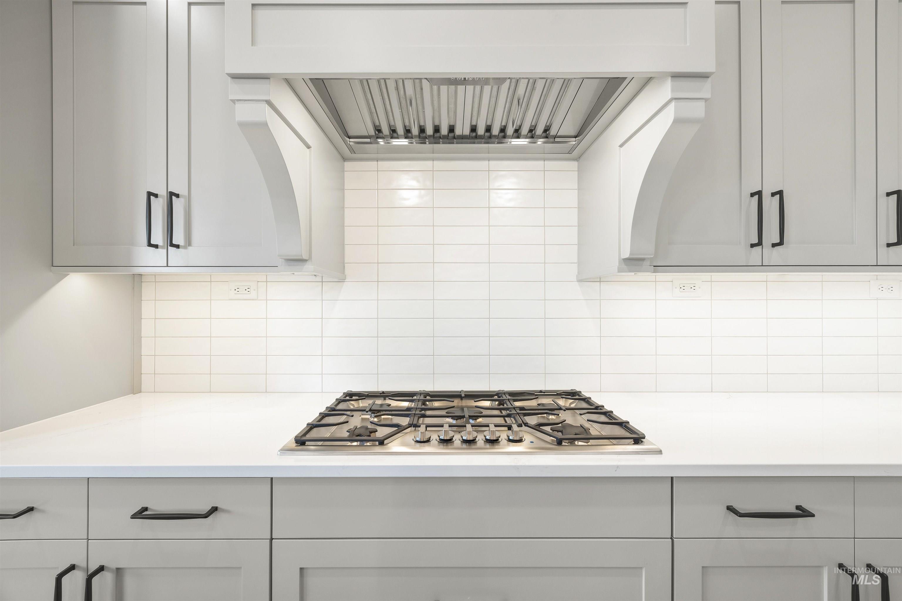 1126 East Crescendo Street Meridian, ID 83642 - Photo 25 of 48 Kitchen with range hood, stainless steel gas cooktop, white cabinetry, and tasteful backsplash