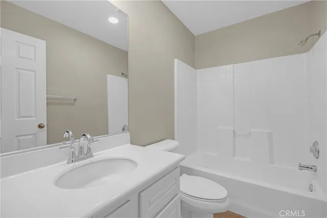 a bathroom with a bathtub shower sink vanity mirror and toilet