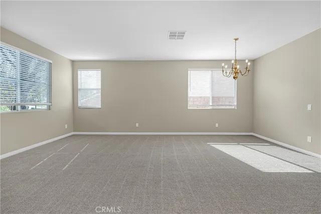 an empty room with windows and chandelier fan