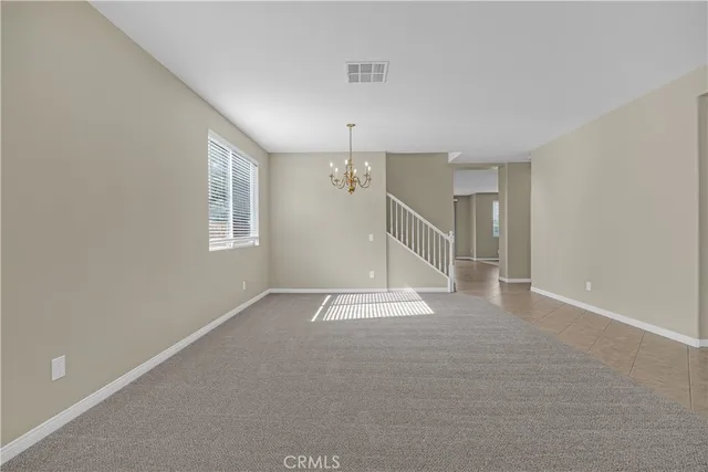 an empty room with windows and chandelier fan