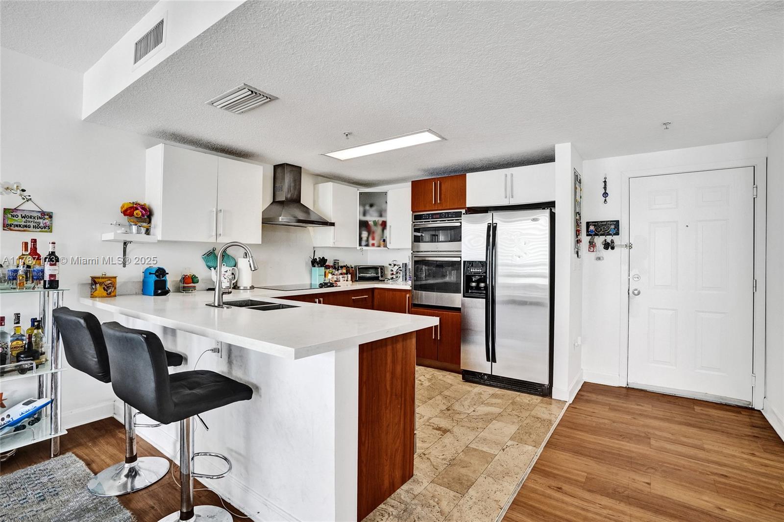 170 Southeast 14th Street, Unit 2907 Miami, FL 33131 - Photo 2 of 30 a kitchen with stainless steel appliances a stove a refrigerator a sink dishwasher and a refrigerator with wooden floor