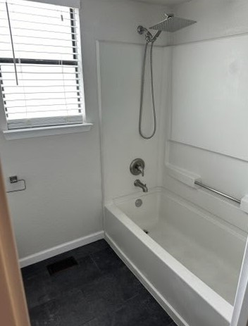 4520 Speedway, Unit A Austin, TX 78751 - Photo 16 of 18 A window-lit bathing area pairs a modern tub and shower with contrasting dark floors.