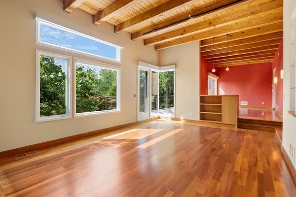 a view of an empty room with a window and wooden floor