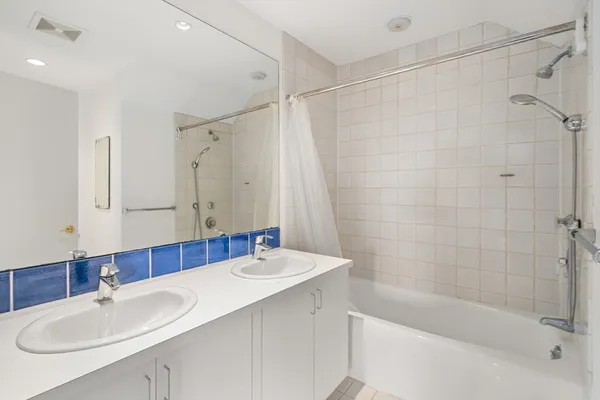 a bathroom with a sink double vanity mirror and a bathtub