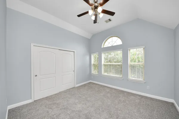 an empty room with a window and a chandelier fan