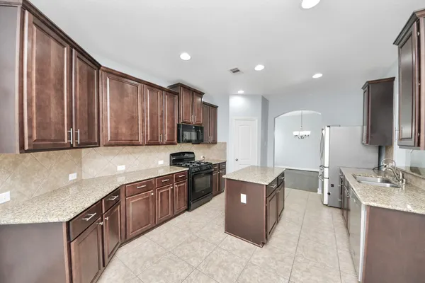 a kitchen with kitchen island granite countertop a sink counter top space appliances and cabinets