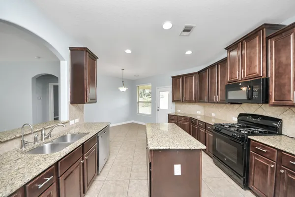 a kitchen with kitchen island granite countertop a sink stove and cabinets