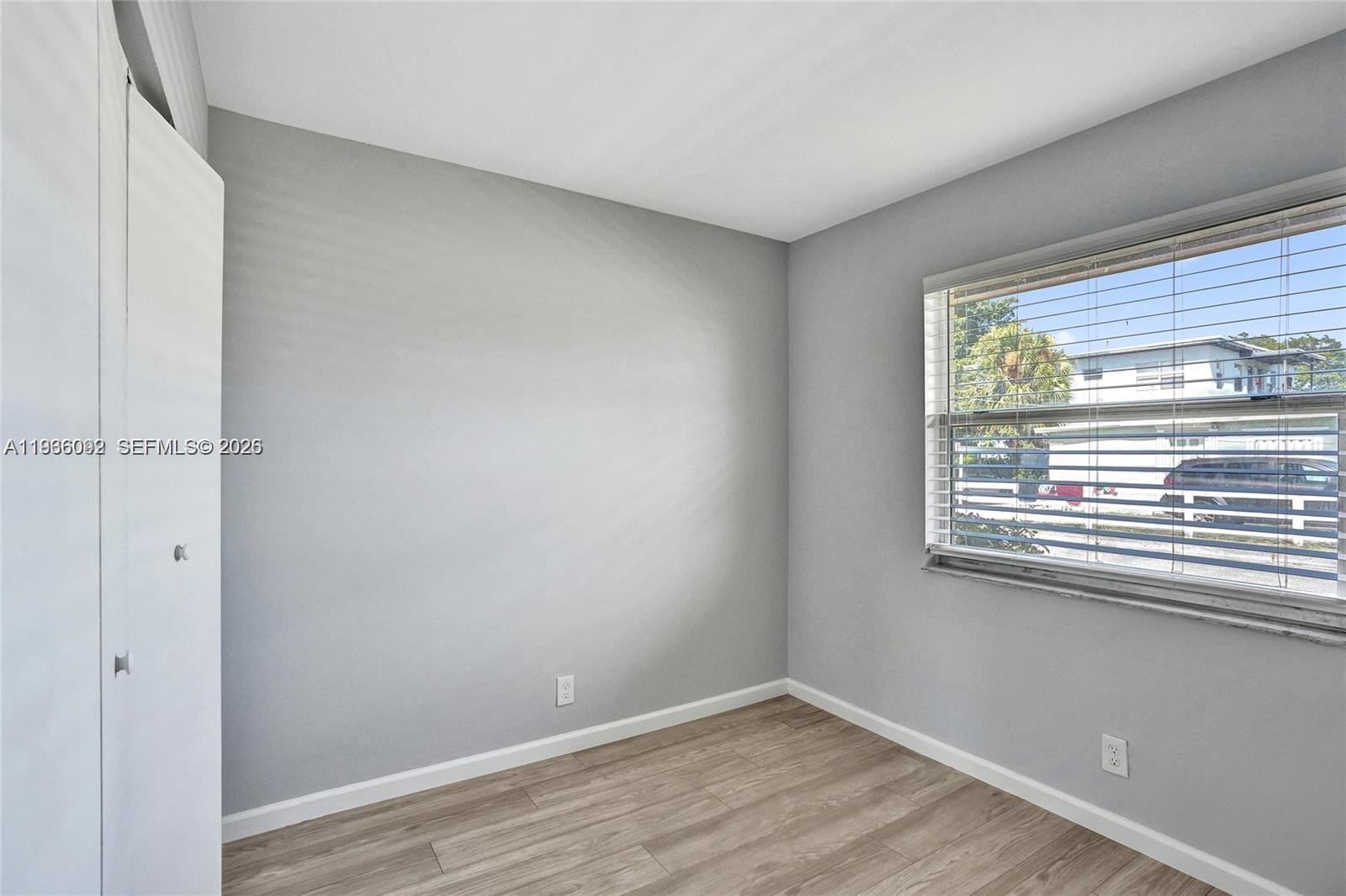 1200 West 31st Street, Unit B Riviera Beach, FL 33404 - Photo 2 of 20 a view of an empty room with wooden floor and a window