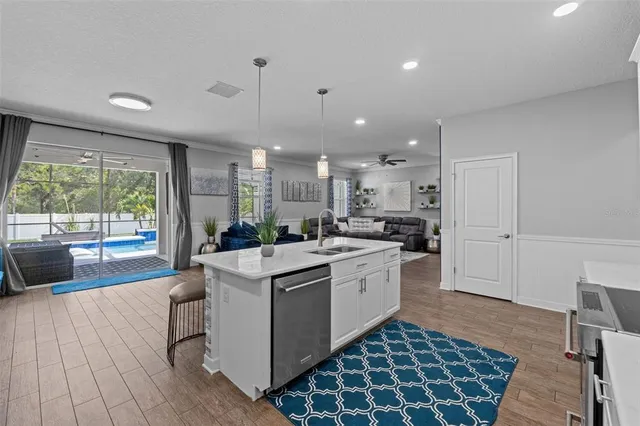 a large kitchen with cabinets chairs and wooden floor