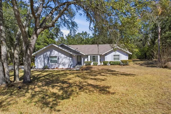 a front view of a house with a garden and trees