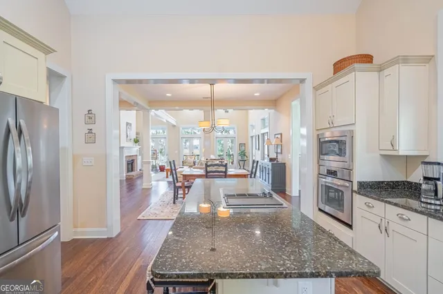 a view of a kitchen with kitchen island a large window a refrigerator and stainless steel appliances