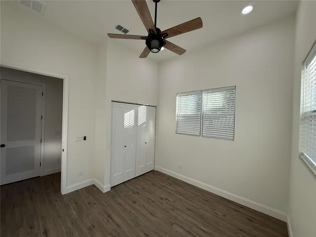 an empty room with wooden floor closet and windows