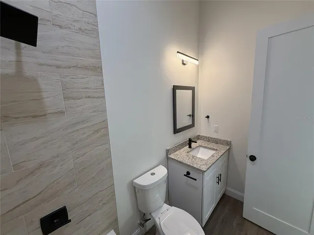 a bathroom with a granite countertop toilet a sink and mirror