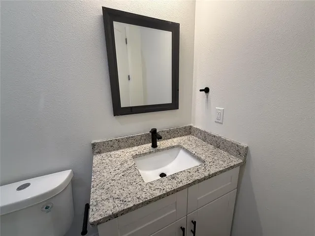 a bathroom with a granite countertop sink and a mirror