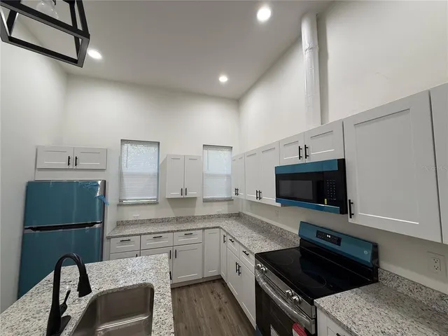 a kitchen with granite countertop a sink appliances and cabinets
