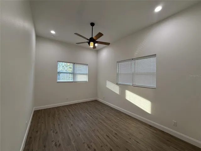 an empty room with wooden floor chandelier and windows