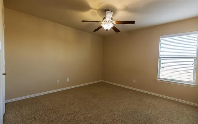 en empty room with windows and chandelier fan
