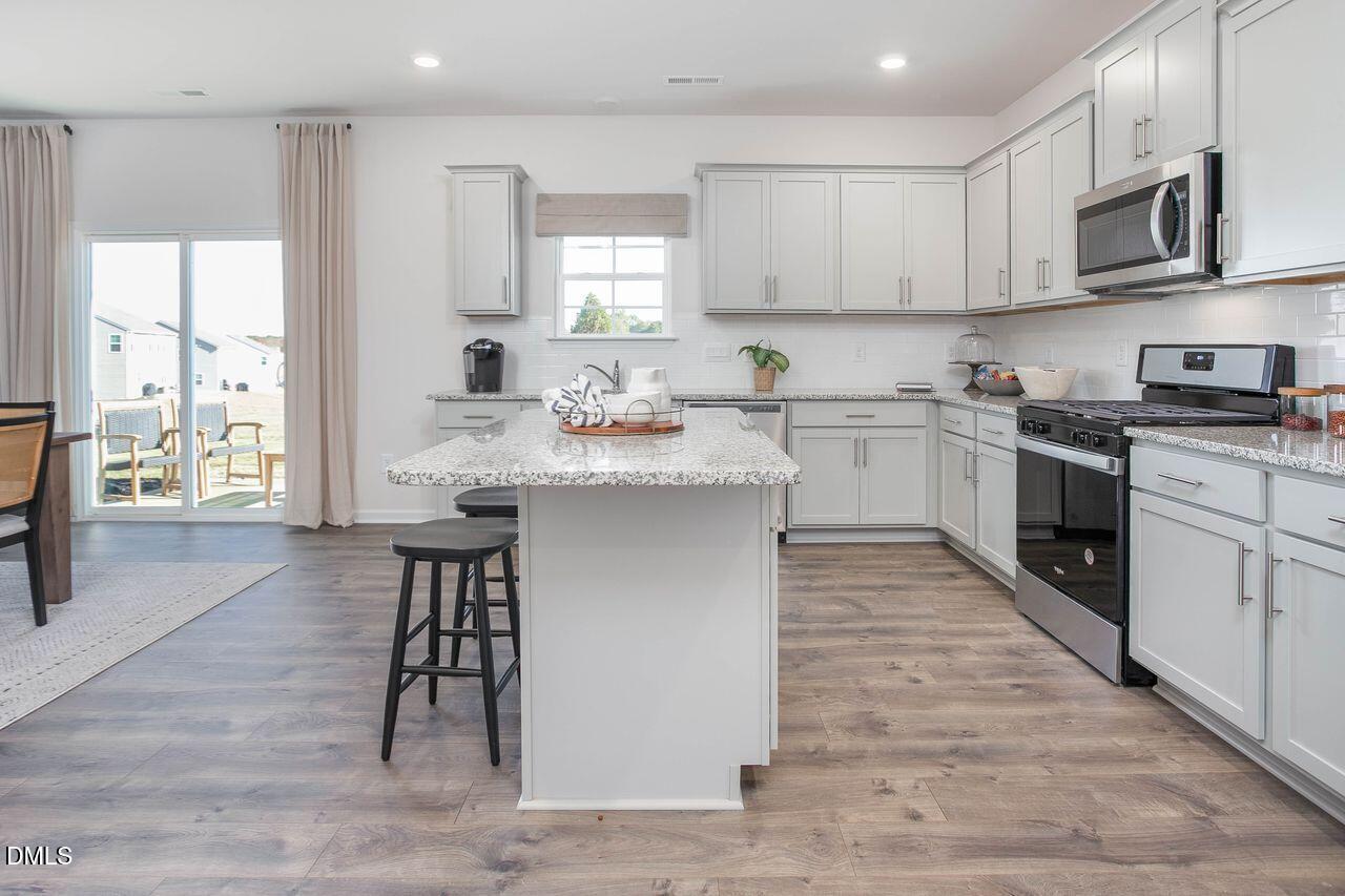 7070 Stockard Road Snow Camp, NC 27349 - Photo 15 of 38 a kitchen with stainless steel appliances granite countertop a stove top oven a sink dishwasher and white cabinets with wooden floor
