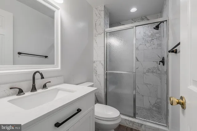 a bathroom with a shower sink vanity mirror and toilet