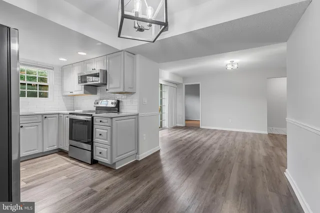 a kitchen with stainless steel appliances a white stove top oven cabinets and a wooden floor