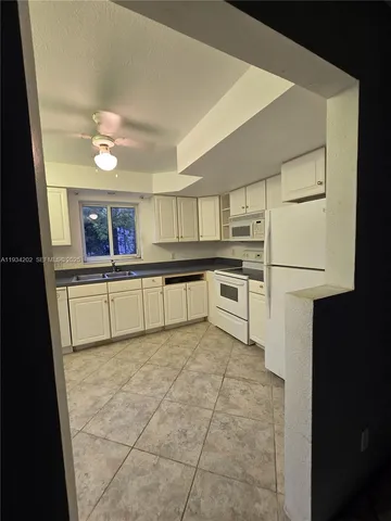 a kitchen with kitchen island granite countertop a stove a sink and a refrigerator with wooden floor