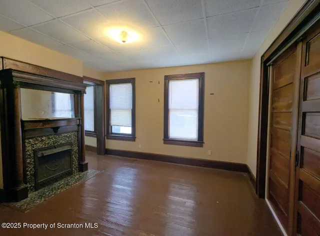 an empty room with wooden floor fireplace and windows