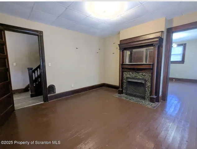 a view of an empty room with wooden floor and a fireplace