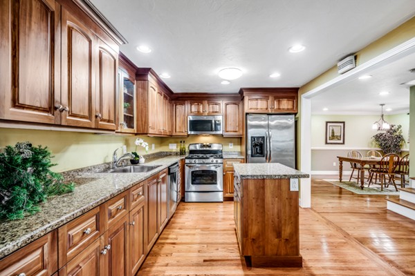 15 Lillian Road Lexington, MA 02420 - Photo 8 of 30 a kitchen with stainless steel appliances granite countertop a stove top oven a sink dishwasher a dining table and chairs with wooden floor
