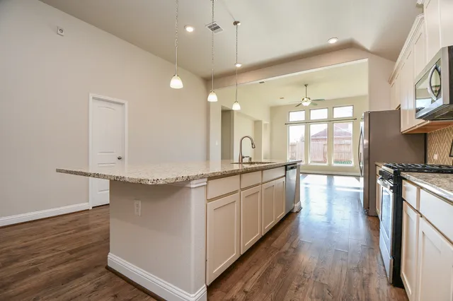 a large kitchen with kitchen island a large island wooden floor and stainless steel appliances