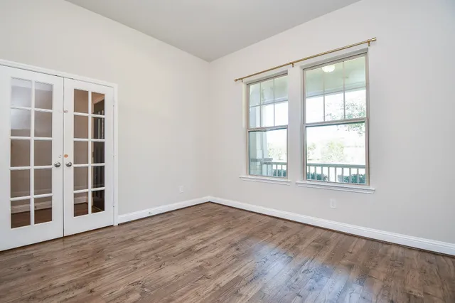 an empty room with wooden floor and windows
