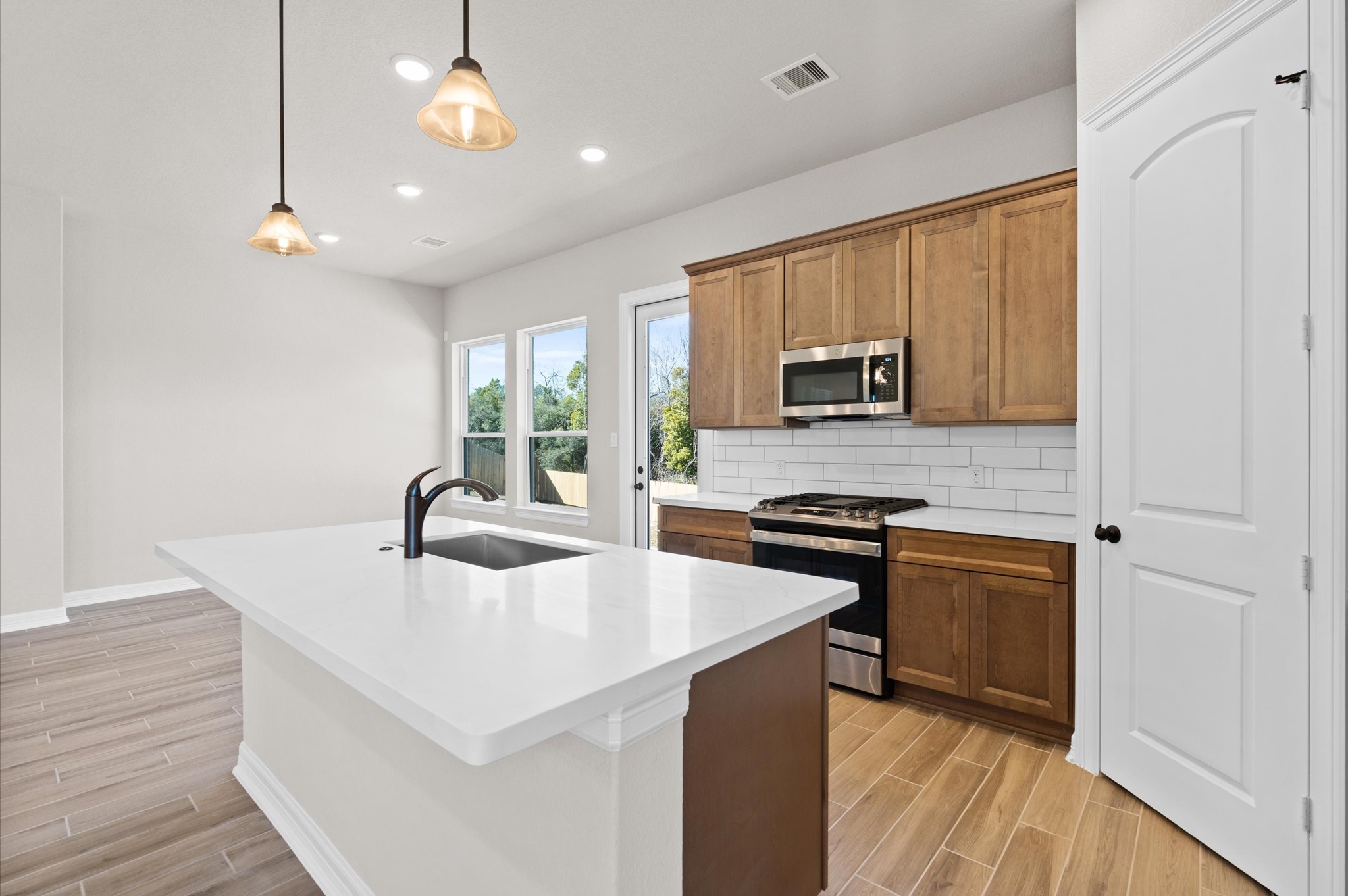 1225 Friendship Trail Seabrook, TX 77586 - Photo 7 of 22 a kitchen with stainless steel appliances granite countertop a sink a stove and a microwave oven with wooden floor