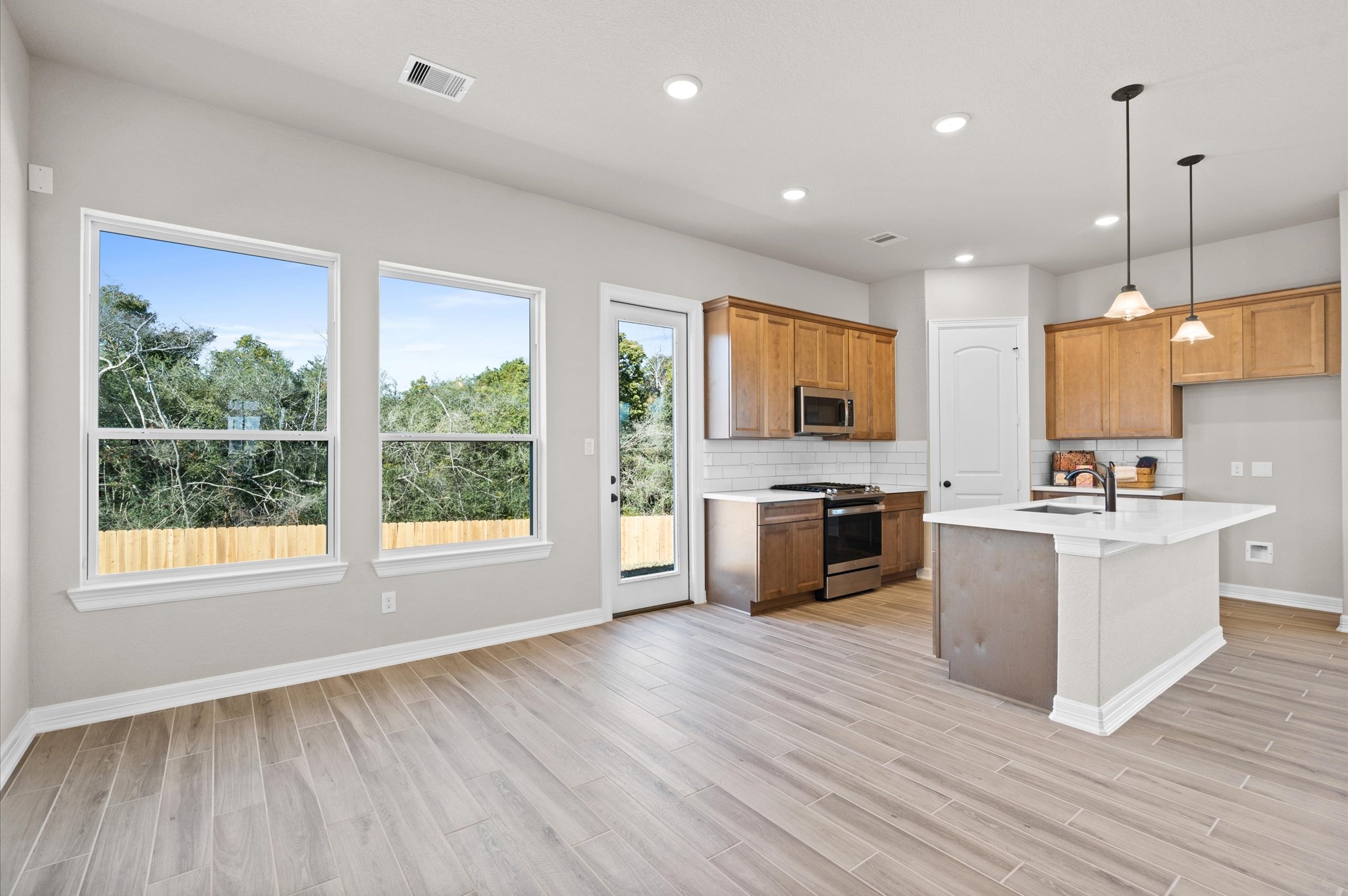 1225 Friendship Trail Seabrook, TX 77586 - Photo 8 of 22 a large kitchen with stainless steel appliances granite countertop a stove a sink dishwasher a refrigerator white cabinets and wooden floor next to a window