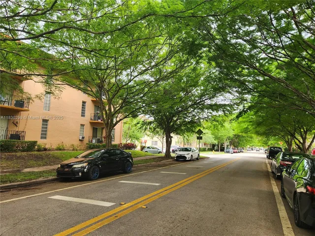 a view of city street with cars parked on the roadside