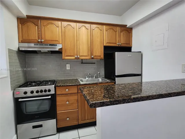 a kitchen with granite countertop a stove a sink and a microwave