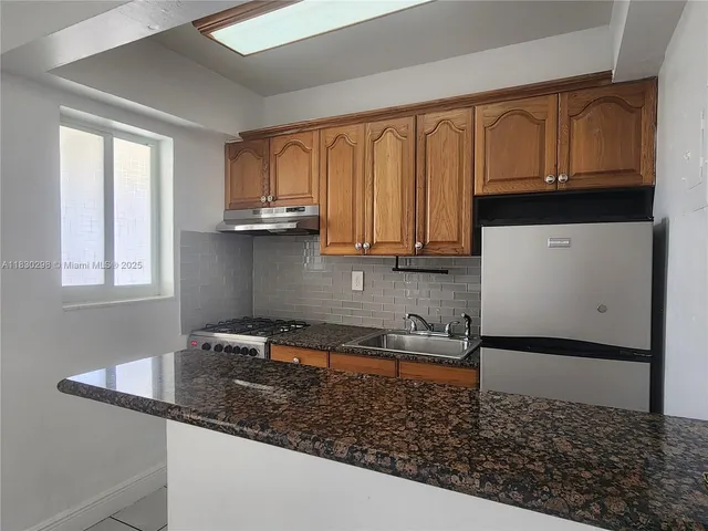 a kitchen with granite countertop a sink a stove and cabinets