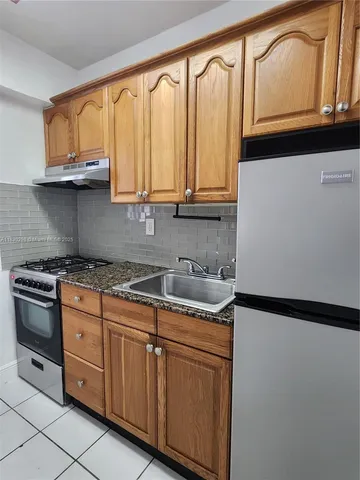 a kitchen with stainless steel appliances granite countertop a sink a stove and white cabinets