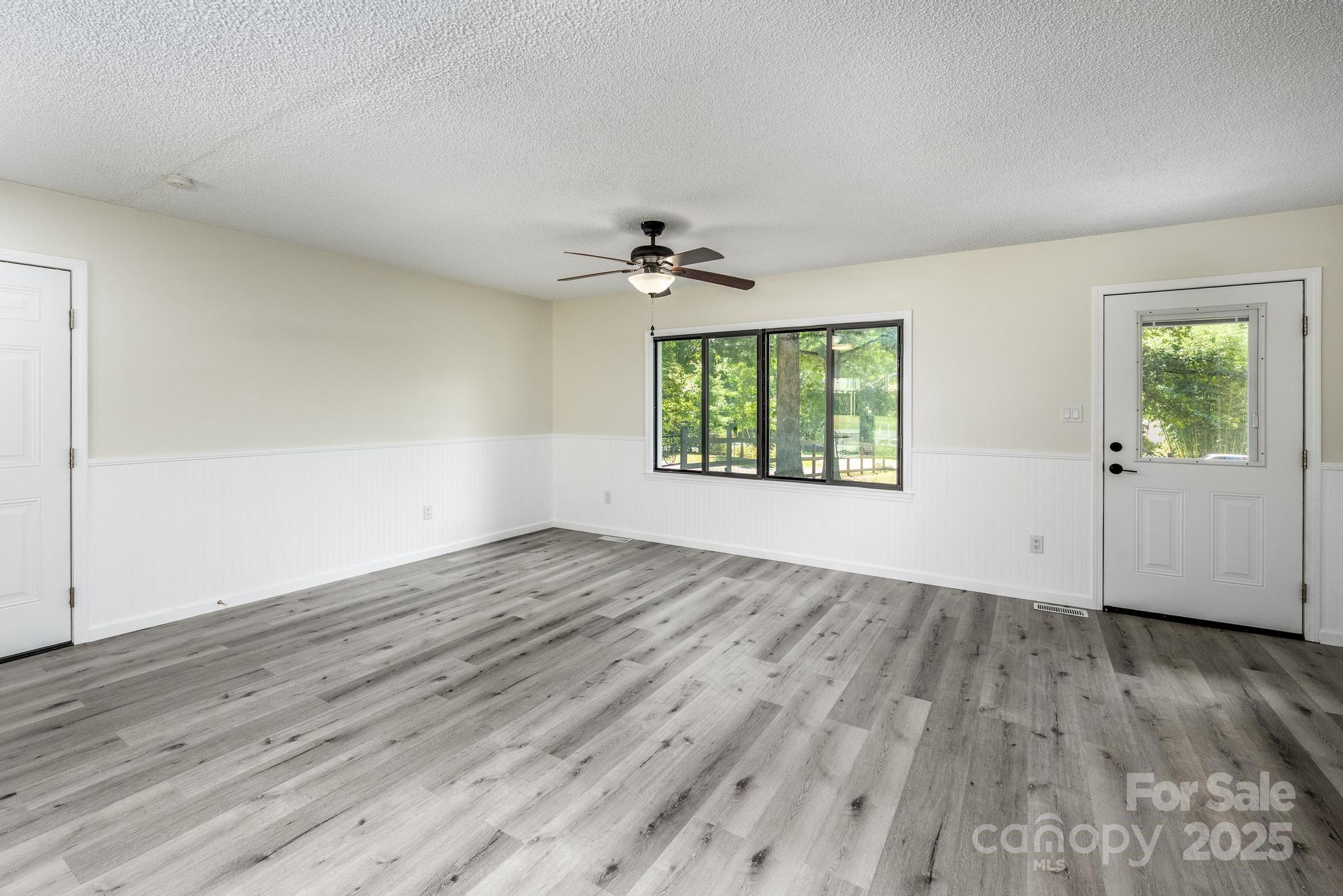 160 Clairmont Road Salisbury, NC 28146 - Photo 11 of 42 an empty room with wooden floor chandelier fan and windows