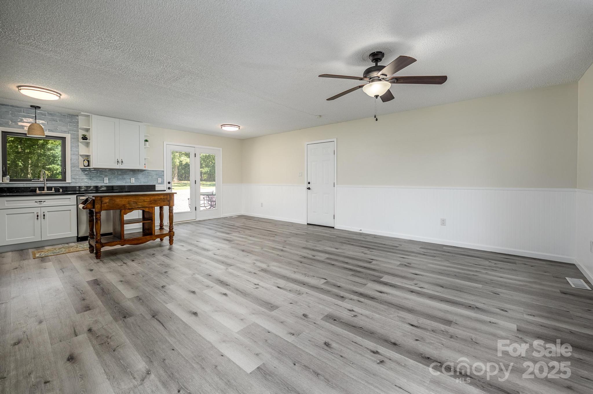 160 Clairmont Road Salisbury, NC 28146 - Photo 10 of 42 an empty room with wooden floor a ceiling fan a fireplace and windows