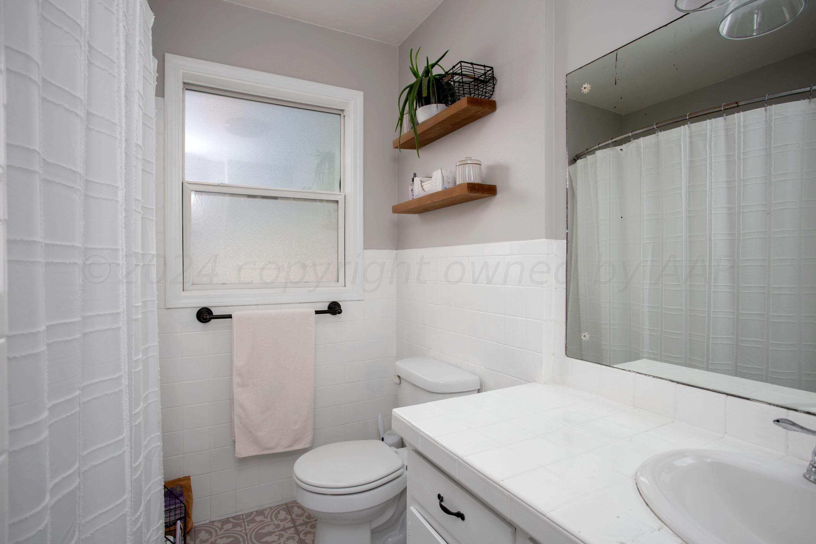 4406 South Bonham Street Amarillo, TX 79110 - Photo 14 of 26 a bathroom with a sink a toilet and shower curtain