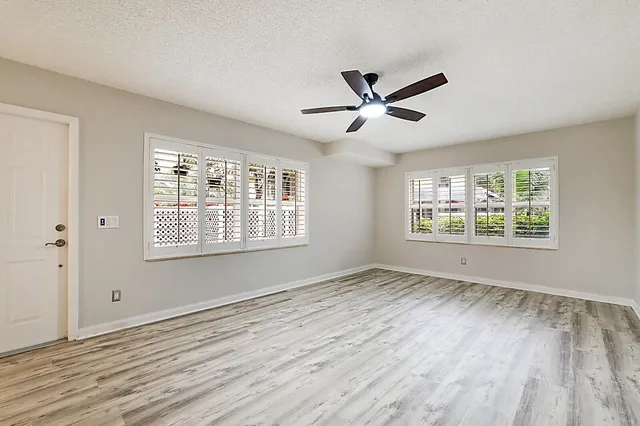 a view of empty room with wooden floor and fan