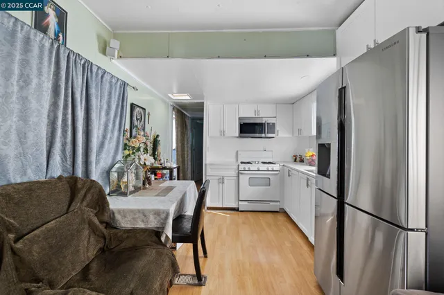 a kitchen with stainless steel appliances a refrigerator a stove a dining table and chairs with wooden floor