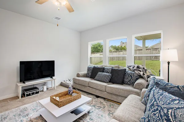 a living room with furniture a flat screen tv and a large window