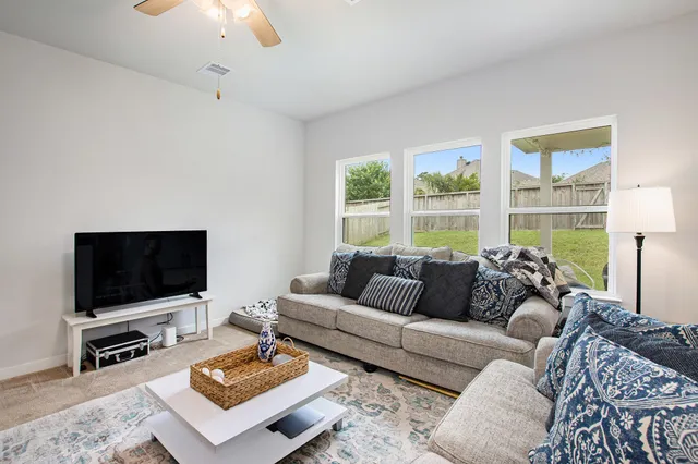a living room with furniture a flat screen tv and a large window
