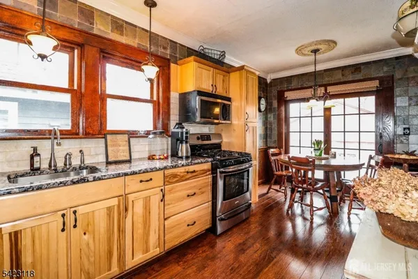 a kitchen with stainless steel appliances granite countertop a stove a sink dishwasher a dining table and chairs with wooden floor